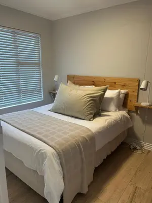 a bedroom with a large bed with a wooden headboard at 3B Sandy Bay in Cape Town