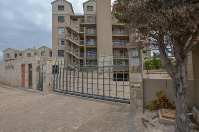 a fence in front of a large building at 3B Sandy Bay in Cape Town