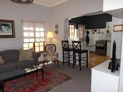 a living room with a couch and a kitchen at Ambleside House Pinelands, Cape Town in Cape Town