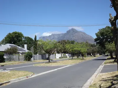 an empty street with a mountain in the background at Ambleside House Pinelands, Cape Town in Cape Town