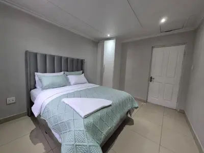 a bedroom with a large bed with a blanket on it at Maglovir economy 3 BEDROOMS BULK in Tiervlei