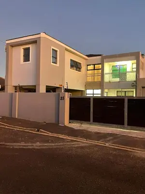 a building with a fence in front of a street at Beach Walk Guest House & Apartments in Cape Town