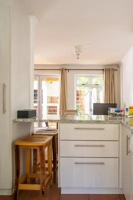 a kitchen with white cabinets and a table and chairs at Stellenbosch Cottage, Entire House and Garden in Stellenbosch
