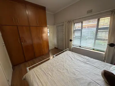 a bedroom with a bed and wooden cabinets and a window at Family Home with Big Garden & Jacuzzi in Welgelegen