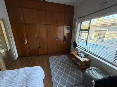 a bedroom with a bed and a window and wooden cabinets at Family Home with Big Garden & Jacuzzi in Welgelegen