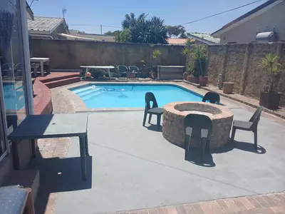 a swimming pool with a table and chairs next to it at Braai and chill getaway in Goodwood