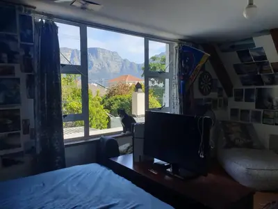 a bedroom with a tv and a cat sitting in a window at Cozy family home in Cape Town