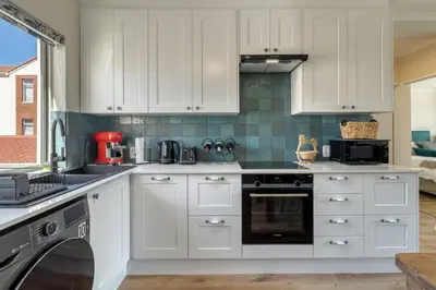 a kitchen with white cabinets and a dishwasher at Sunny Apartment Harbour Island in Gordonʼs Bay