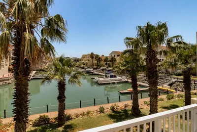 a view from a balcony of a river with palm trees at Sunny Apartment Harbour Island in Gordonʼs Bay
