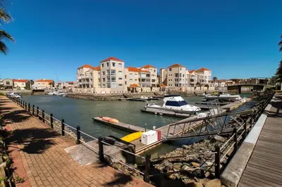 a marina with boats in the water next to buildings at Sunny Apartment Harbour Island in Gordonʼs Bay