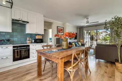 a kitchen with a wooden table and chairs in a kitchen at Sunny Apartment Harbour Island in Gordonʼs Bay