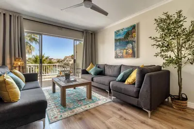 a living room with a couch and a table at Sunny Apartment Harbour Island in Gordonʼs Bay