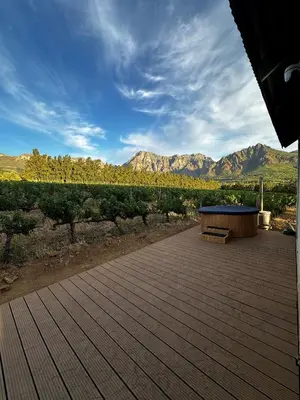 a wooden deck with a bench and mountains in the background at Genadendaal Vineyard Villa in Paarl