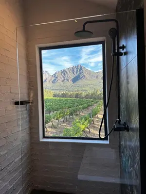 a shower with a window with a view of a mountain at Genadendaal Vineyard Villa in Paarl