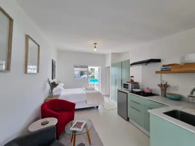 a kitchen with a bed and a red chair in a room at Northcliff House in Hermanus
