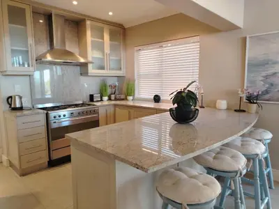 a kitchen with a large island with bar stools at Paradise Piet Haven in Hermanus