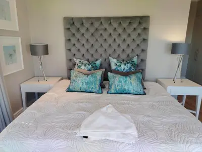 a large bed in a bedroom with two lamps at Paradise Piet Haven in Hermanus