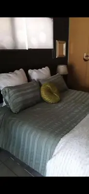 a bed with a yellow pillow and pillows on it at Carol's Place in Somerset West