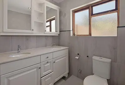a bathroom with a toilet and a sink and a mirror at Briza Breeze in Cape Town