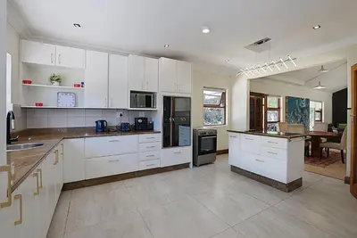 a large kitchen with white cabinets and a table at Briza Breeze in Cape Town