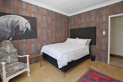 a bedroom with a bed and a painting of a horse at Briza Breeze in Cape Town