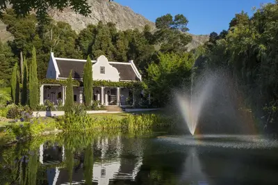 a house with a fountain in the middle of a pond at La Providence in Franschhoek