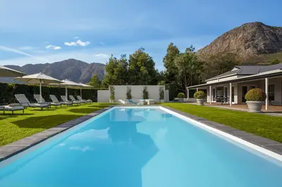 a swimming pool in a yard with mountains in the background at La Providence in Franschhoek
