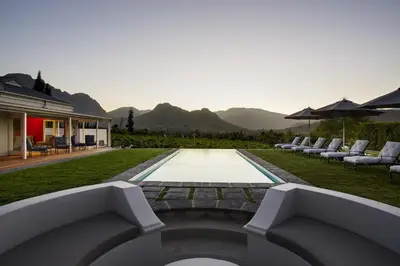 a swimming pool in a yard with lounge chairs and an infinity at La Providence in Franschhoek