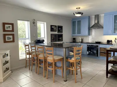 a kitchen with blue cabinets and a island with bar stools at Secret Coastal Garden in Hermanus