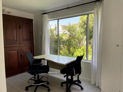 a table and chairs in a room with a large window at Secret Coastal Garden in Hermanus