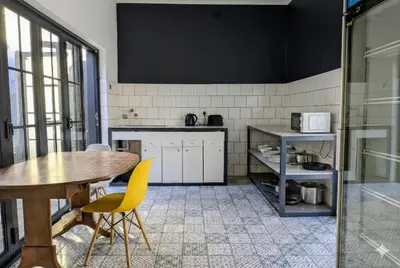 a kitchen with a wooden table and yellow chairs at Modern Boho Loft- Observatory in Cape Town