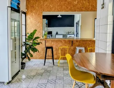 a kitchen with a wooden table and yellow chairs at Modern Boho Loft- Observatory in Cape Town