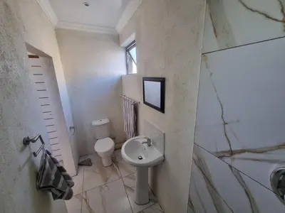 a white bathroom with a sink and a toilet at Bird Retreat in Zeekoevlei