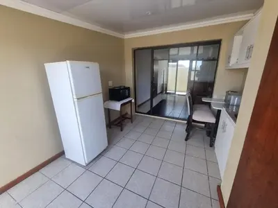 a kitchen with a refrigerator and a table and chairs at Bird Retreat in Zeekoevlei
