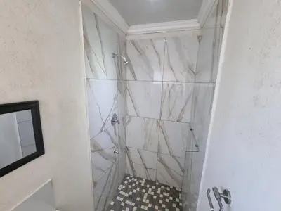 a bathroom with a shower with marble walls at Bird Retreat in Zeekoevlei