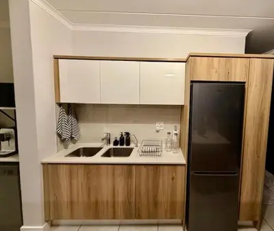 a kitchen with a sink and a black refrigerator at Luxury Coastal Escape in Strand in Somerset West