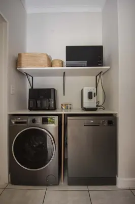 a kitchen with a washing machine and a microwave at Luxury Coastal Escape in Strand in Somerset West