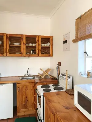 a kitchen with wooden cabinets and a stove top oven at Eensgevonden Vineyard Cottages in Rawsonville