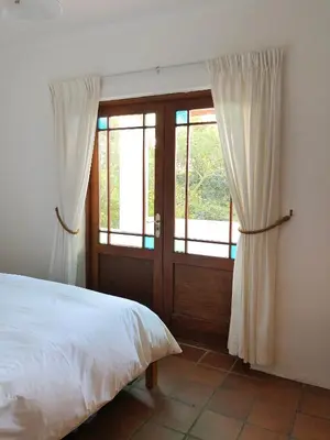 a bedroom with a bed and a sliding glass door at Eensgevonden Vineyard Cottages in Rawsonville