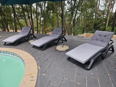 three lounge chairs and an umbrella next to a pool at The Lineage Lodge in Elgin