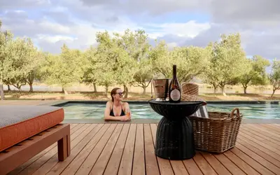 a woman sitting next to a swimming pool at Olijvenkraal Winelands Lodge in Paarl