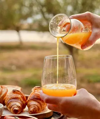 a person pouring orange juice into a wine glass at Olijvenkraal Winelands Lodge in Paarl