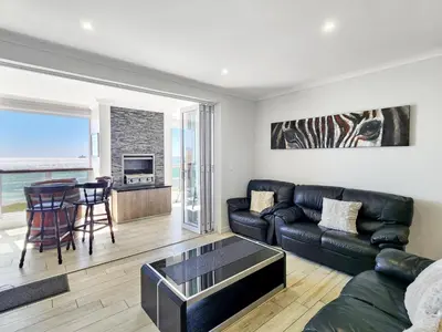 a living room with a couch and a table at Neptune Isle Oceanfront 3-Bed with Pool in Cape Town