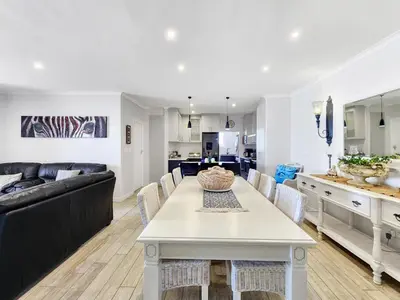 a kitchen and living room with a table and a couch at Neptune Isle Oceanfront 3-Bed with Pool in Cape Town