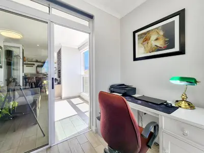 a desk with a red chair and a picture of a dog at Neptune Isle Oceanfront 3-Bed with Pool in Cape Town