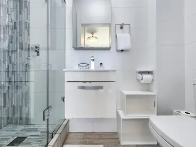 a white bathroom with a sink and a shower at Neptune Isle Oceanfront 3-Bed with Pool in Cape Town