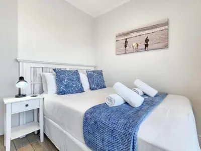 a bedroom with a bed with blue and white pillows at Neptune Isle Oceanfront 3-Bed with Pool in Cape Town