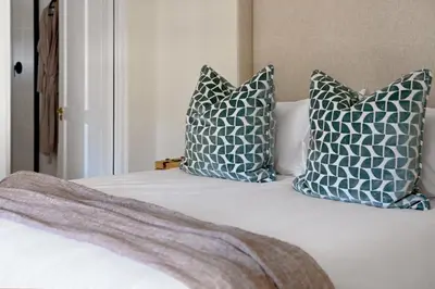 a bed with blue and white pillows on it at The Farm Cottage in Franschhoek