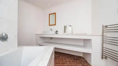a white bathroom with a sink and a tub at Birdsong in Hermanus