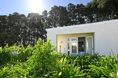 a white house in the middle of a garden at The Little Vineyard Cottage in Franschhoek
